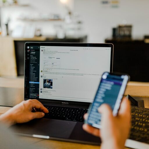 Stock image of person holding phone while using laptop.