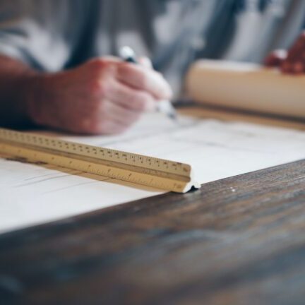 Stock image of man drawing on draft paper with an architect's scale.
