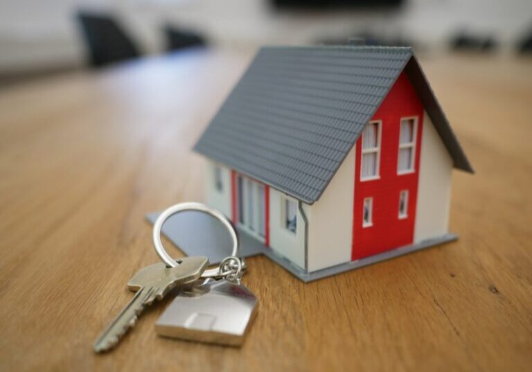 Stock image of a small house model next to a key and house keychain.